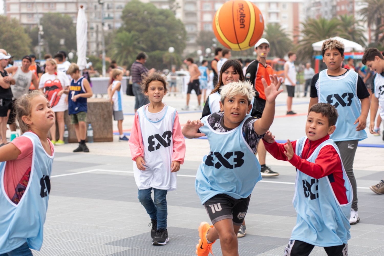 Pessoas jogando basquete em quadra poliesportiva pública na orla